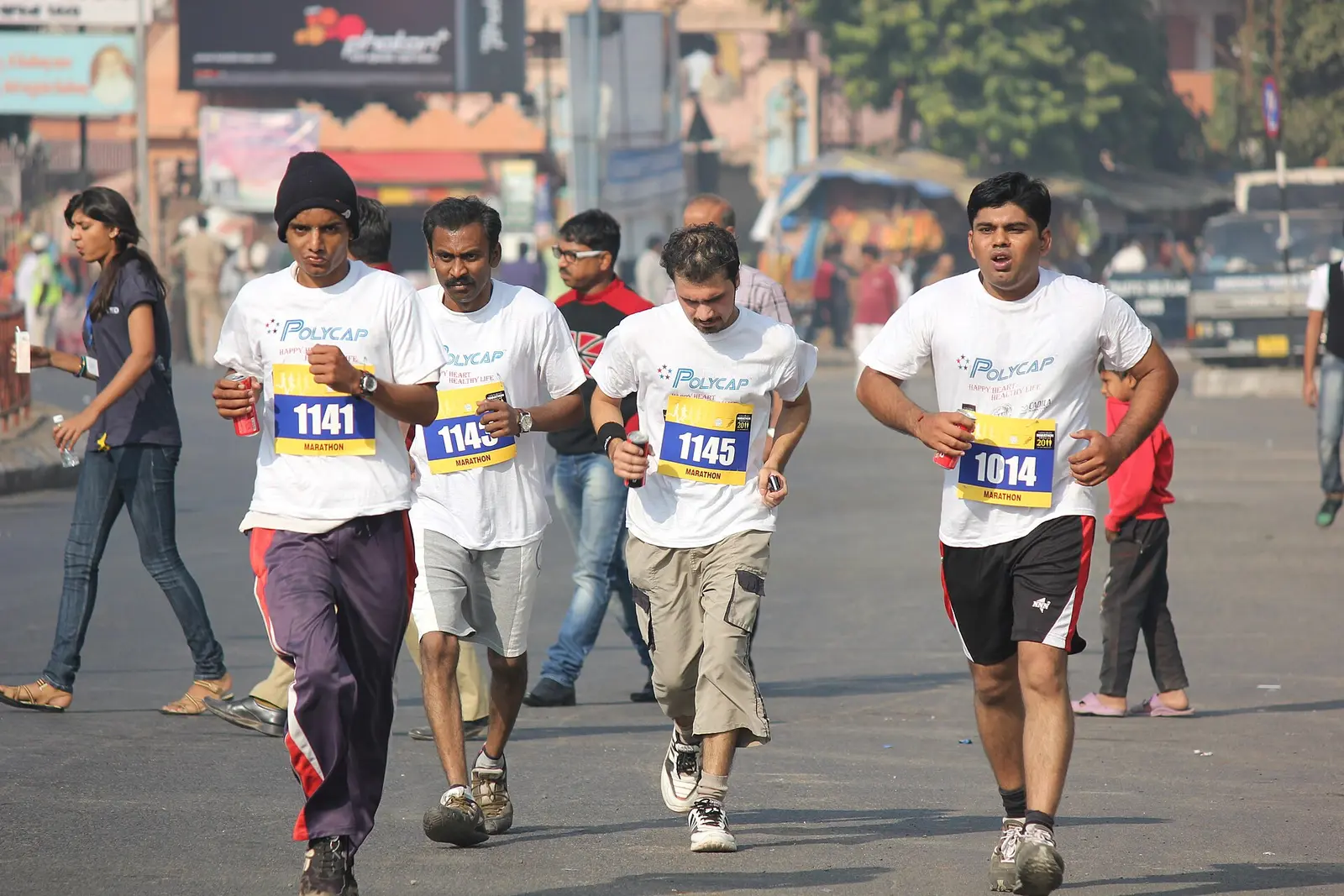 Runners with race bibs on a road during the Ahmedabad Marathon