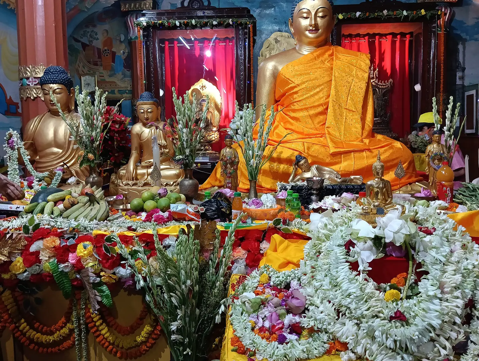 Buddha statues decorated with garlands and offerings for Buddha Jayanti at a Mahabodhi Society hall