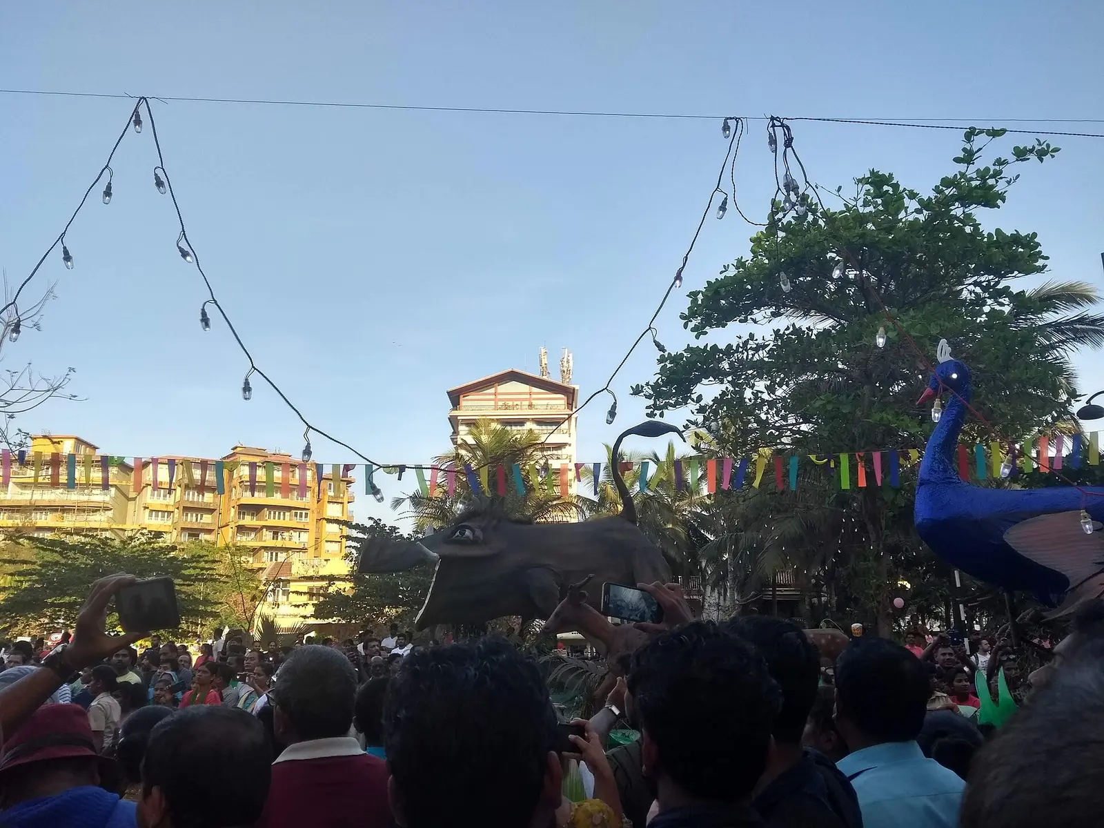Crowd under hanging lights and giant carnival figures in Panjim during Carnival in Goa