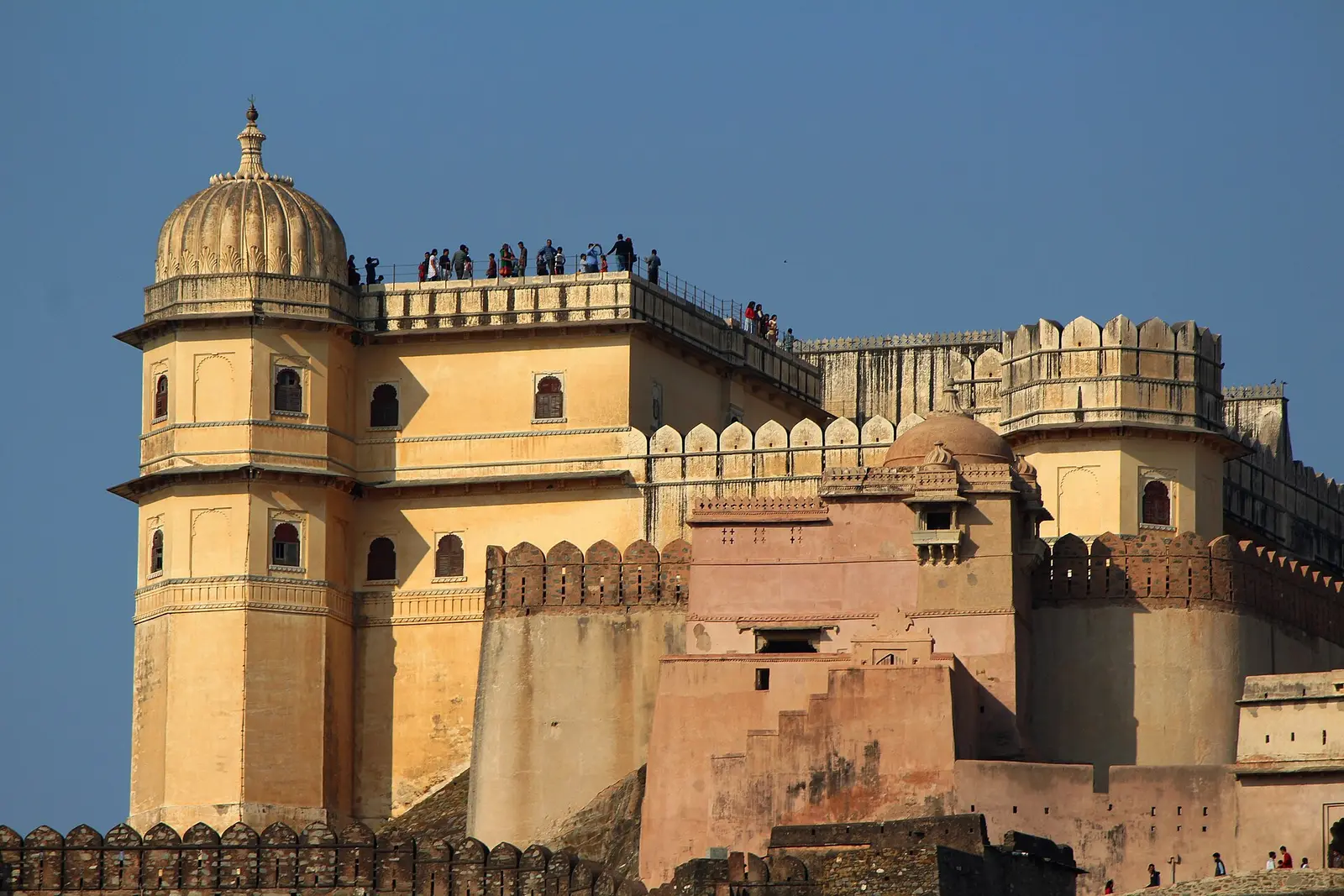 The golden-stone palace towers of Kumbhalgarh Fort under a blue sky