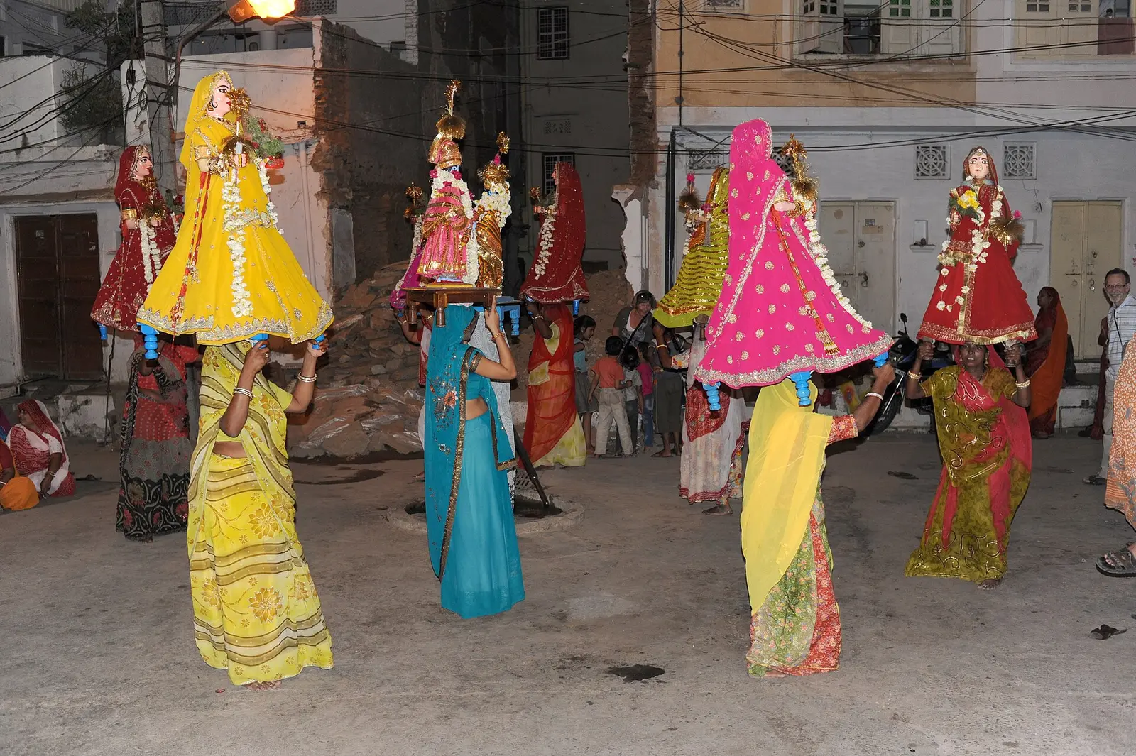 Women carrying decorated Gangaur figures on a street at the Mewar Festival in Udaipur