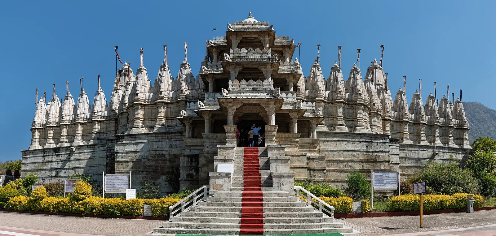 The marble Ranakpur Jain Temple with its many spires above a red-carpeted stair